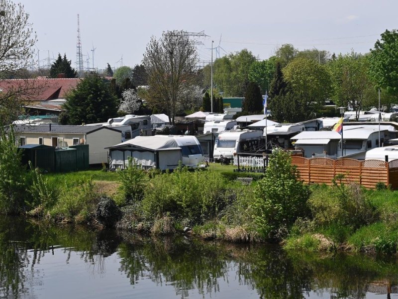 Bewohnte und unbewohnte Campingfahrzeuge stehen auf einem Campingplatz am Havelkanal nebeneinander.