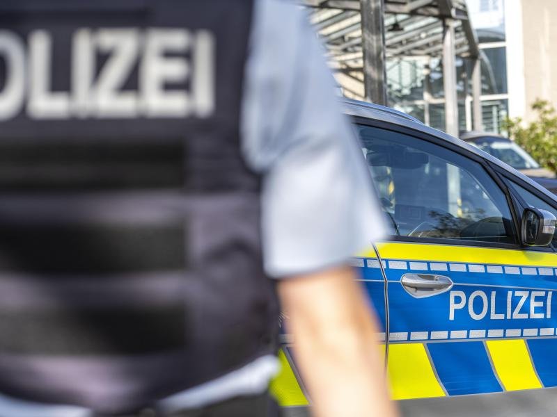 Ein Polizist steht vor einem Streifenwagen.
