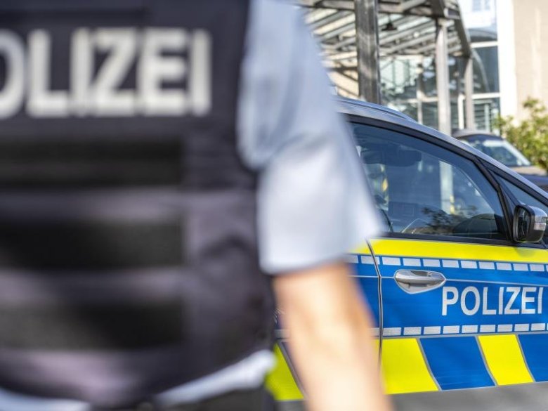 Ein Polizist steht vor einem Streifenwagen.