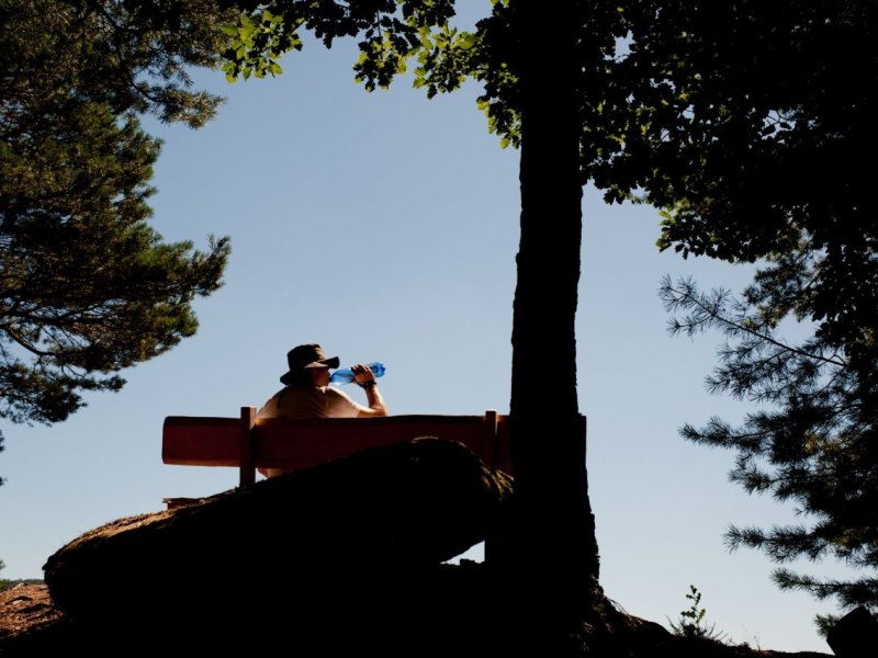 Ein Mann sitzt auf einer Bank und trinkt