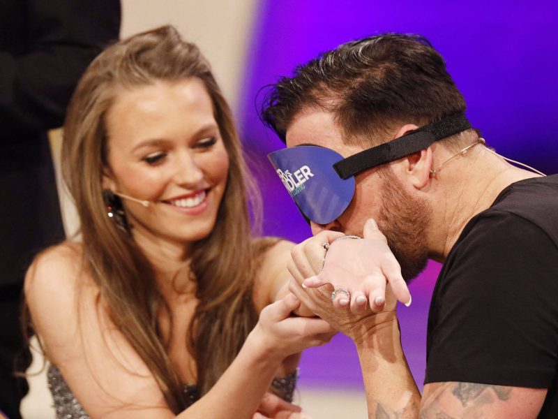 Michael Wendler küsst mit verbundenen Augen Laura Müllers Arm.