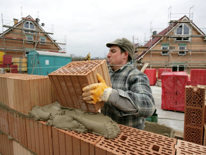 Bauarbeiter mauert eine Außenwand eines.jpg