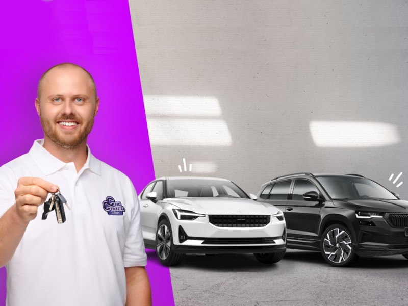 Ein CarCoach von MeinAuto.de steht vor zwei Neuwagen und hält die Autoschlüssel in der Hand.