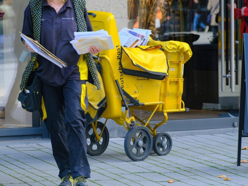 Deutsche Post: Briefträger teilt Post aus.