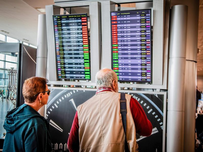 Urlaub in den Osterferien Paar sieht sich Abflugtafel im Flughafen an