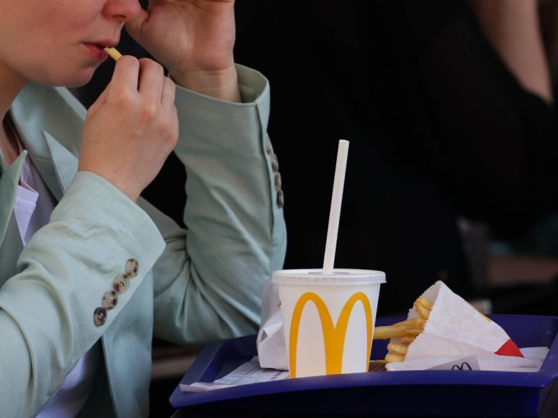 McDonald's-Kundin mit Pommes und Getränk auf dem Tablett
