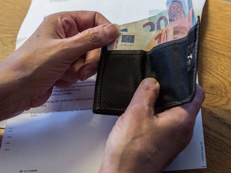 Ältere Frau fasst ins Portemonnaie Euroscheine Rechnung