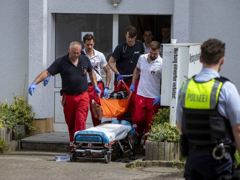 Rettungskräfte tragen verletzte Person aus Haus