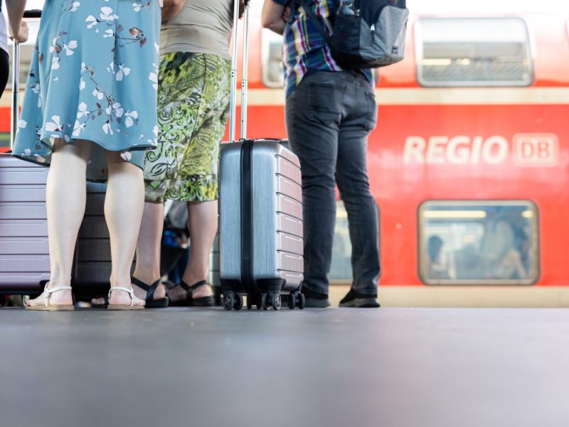Fahrgäste warten mit ihrem Gepäck vor einem Regionalexpress der Deutschen Bahn in NRw