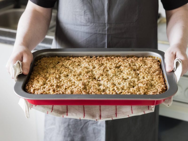 Bäcker hält ein Backblech Streuselkuchen