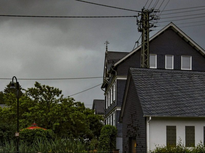 Dunkle Wolken am Himmel hinter Häusern und Bäumen