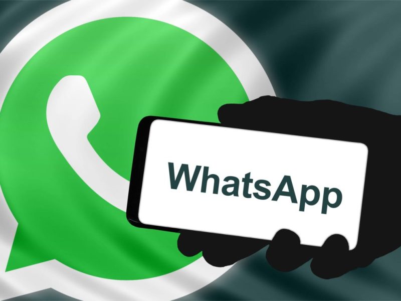 Ein Smartphone mit dem Whatsapp-Schriftzug ist vor einem Whatsapp-Logo zu sehen.