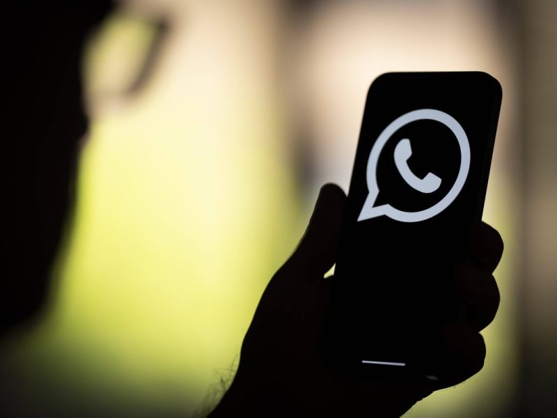 Mann schaut auf Whatsapp-Symbol auf Smartphone