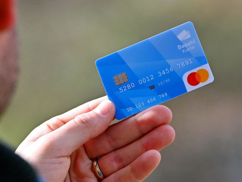 Ein Mann hält eine Asyl-Bezahlkarte in der Hand.